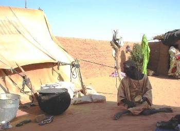 A disabled child sitting in the shade by a tent